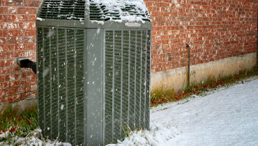 Modern high efficiency air conditioner under falling snow | Aire Serv of Wilmington