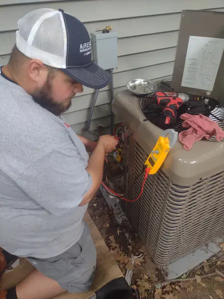 Hartland, WI, technician fixing outdoor HVAC unit.