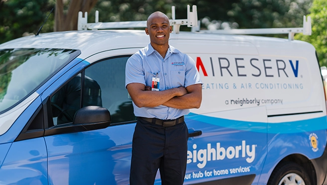 Aire Serv technician standing with their arms crossed in front of an Aire Serv van.