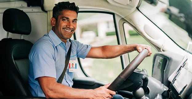 Aire Serv technician smiling from the driver's seat of an Aire Serv van.