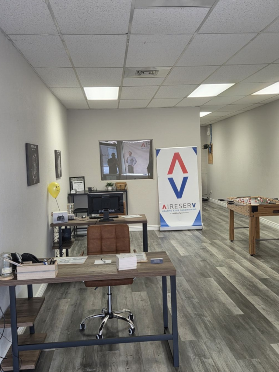 A clean, modern interior view of the Aire Serv of E Glendale-Peoria office featuring professional wood flooring and a meeting area for staff and clients.