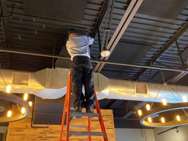 Aire Serv Technician working on installing ductwork inside building
