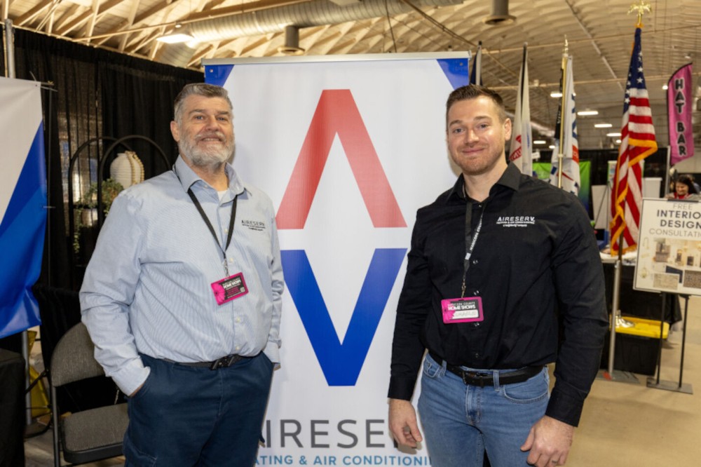 Owners, Chuck and Charles, family smiling together at the Aire Serv booth during the Maricopa Home and Gardens Show.