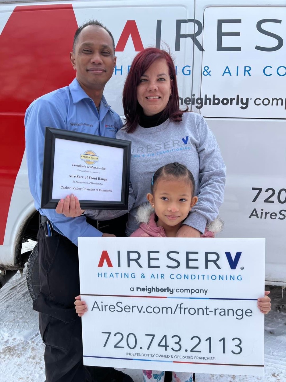 Aire Serv of Front Range owners holding an award while their daughter holds a company branding sign.