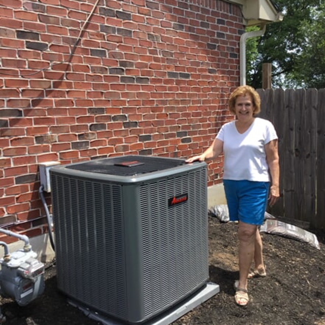 Happy customer standing next to a newly installed outdoor AC unit
