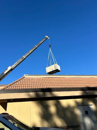 Crane Lifting HVAC Unit Over Building