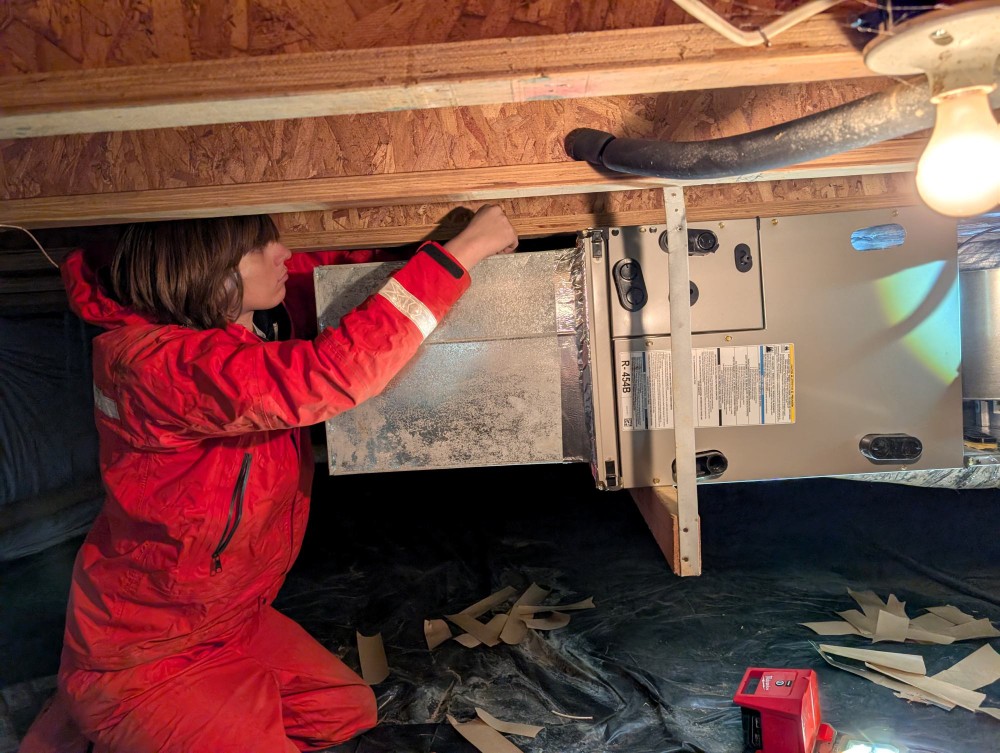 Technician repairing a furnace in an attic