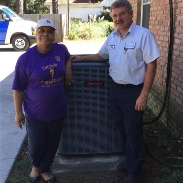 Technician And Homeowner Standing Next To A Newly Installed Air Conditioning Unit