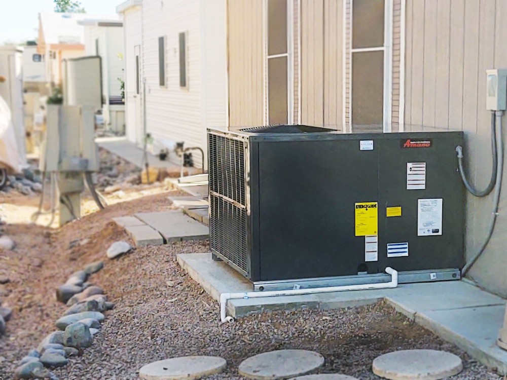 Outdoor HVAC unit installed on a concrete pad beside a residential home, surrounded by gravel landscaping and stepping stones.