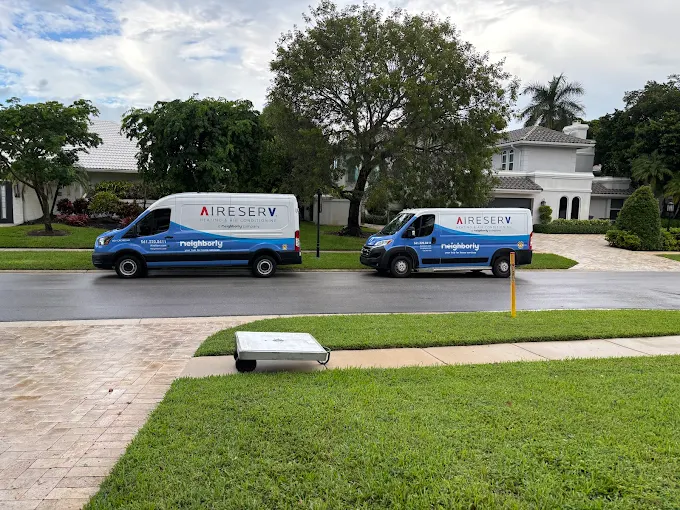 Two Service Trucks Parked Outside A Residential Home