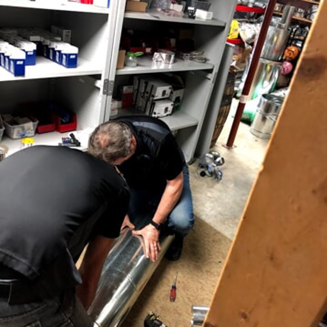 Two HVAC technicians working on ducting inside the Aire Serv of Knoxville shop