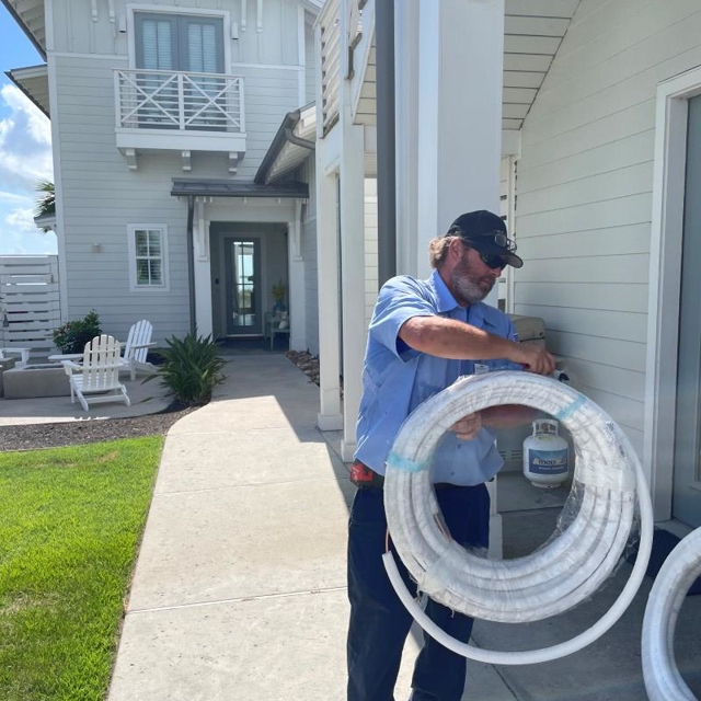 HVAC Technician Working Outside Home Carrying Tubing Wiring