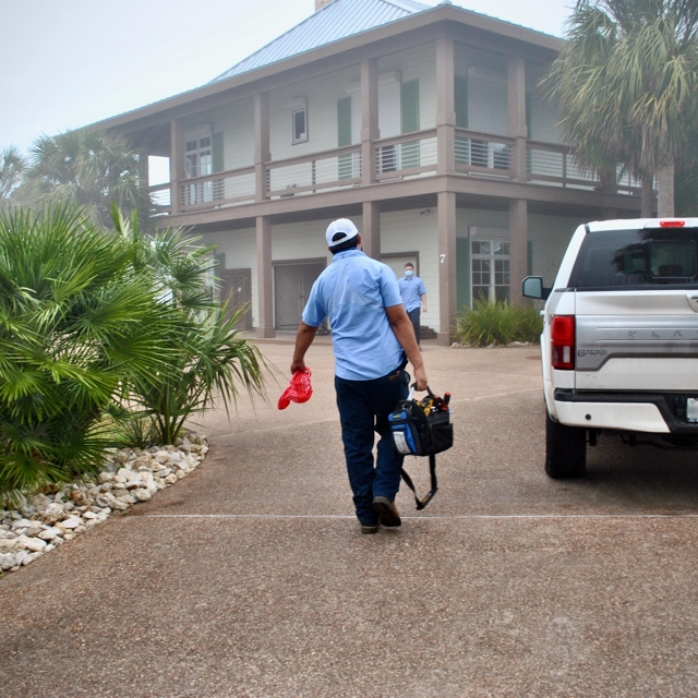 Aire Serv of Coastal Bend HVAC technician carrying a tool bag while walking toward a home.
