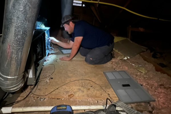 Technician Repairing a Furnace in an Attic