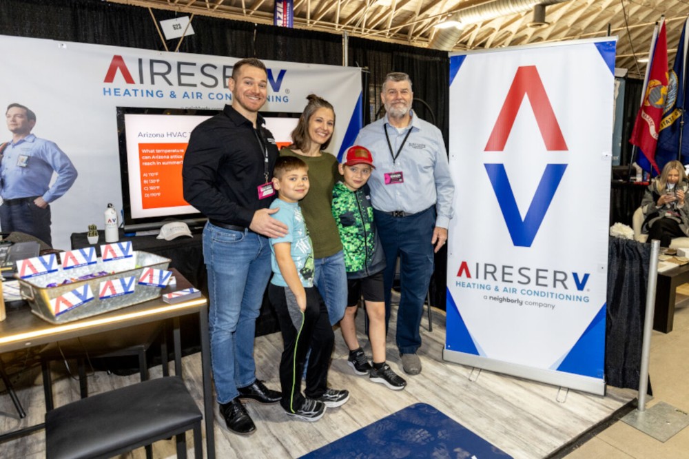 The Van Liew family, owners of Aire Serv of E Glendale-Peoria, smiling at their professional exhibit booth during the Maricopa Home and Gardens Show.