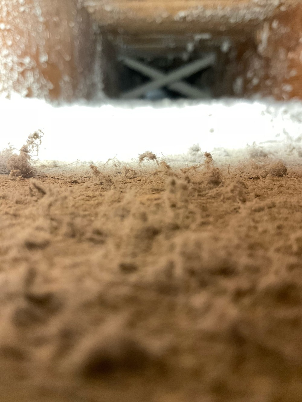 Close-up of HVAC ductwork with heavy accumulation of dust, pet dander, and debris build up.