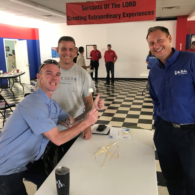 two aire serv men and a mr rooter man at a booth