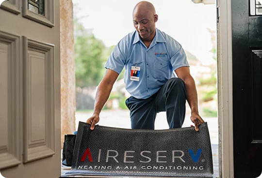 Aire Serv technician laying down branded doormat.