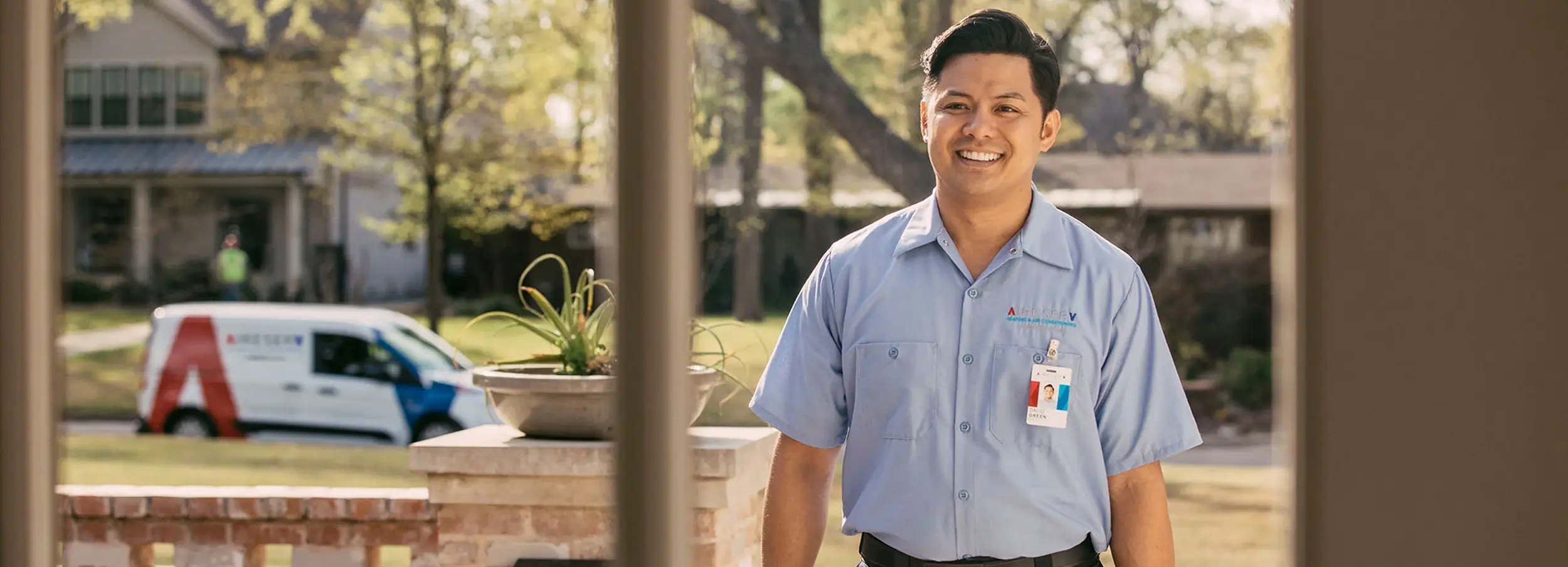 A smiling male Aire Serv technician arriving at a customer's home.