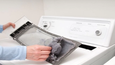 A man removes built-up lint and dust from his dryer’s lint filter. | Aire Serv of Western North Carolina