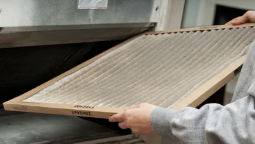 Homeowner changing their dirty air filter.
