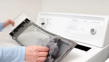 A man removes lint from his clothes dryer’s lint trap. | Aire Serv of North Central Arizona
