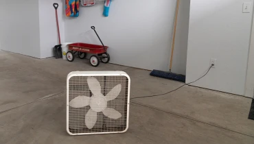 Box fan in middle of a mostly empty garage