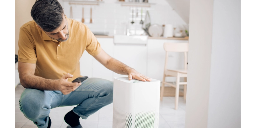 A man sets up an air purifier with an app on his mobile phone.