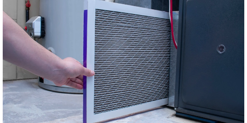 A person changing an air filter on a high efficiency furnace.