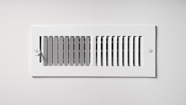 A white metal grate covers an air duct for heating and cooling. | Aire Serv of North Central Arizona