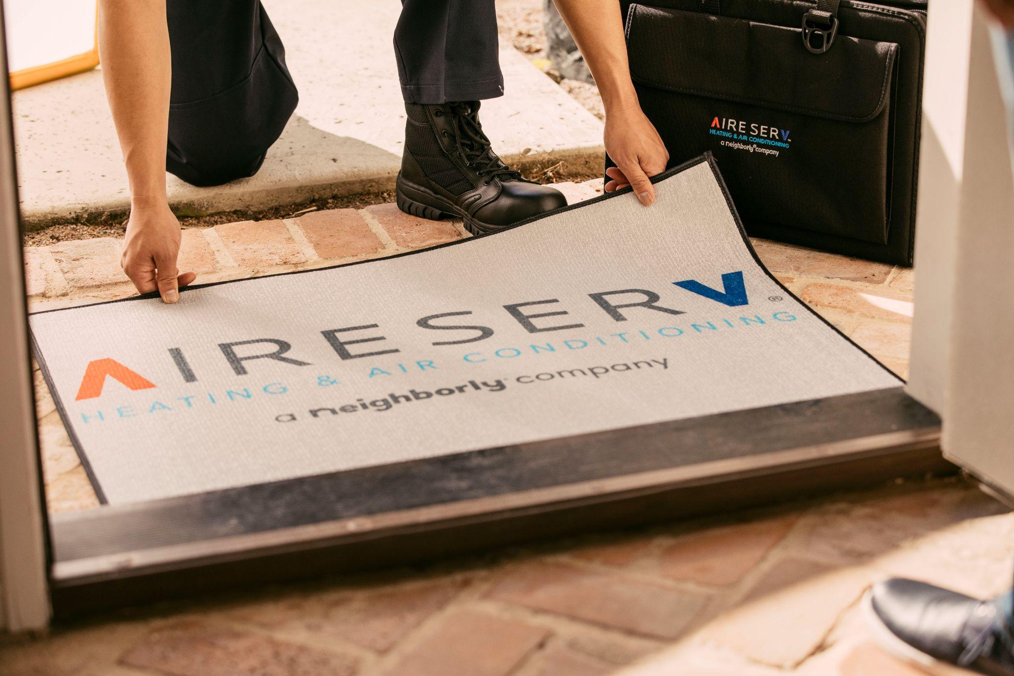 Aire Serv branded doormat being placed outside a home.