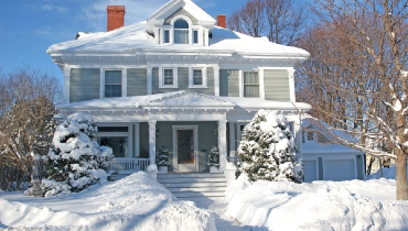 Large, older residential home covered with a lot snow