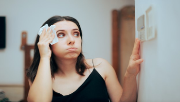 Woman feeling hot during summer setting her thermostat | Aire Serv® of Springfield, IL
