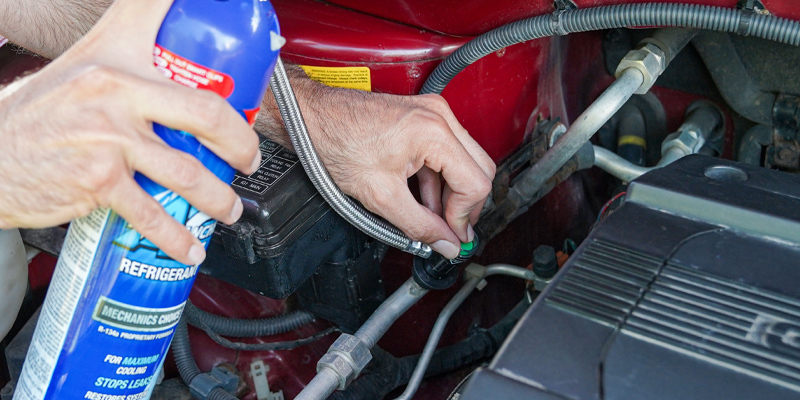Man using can of refrigerant to improve car AC performance