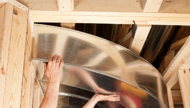 Professionals installing curved ductwork