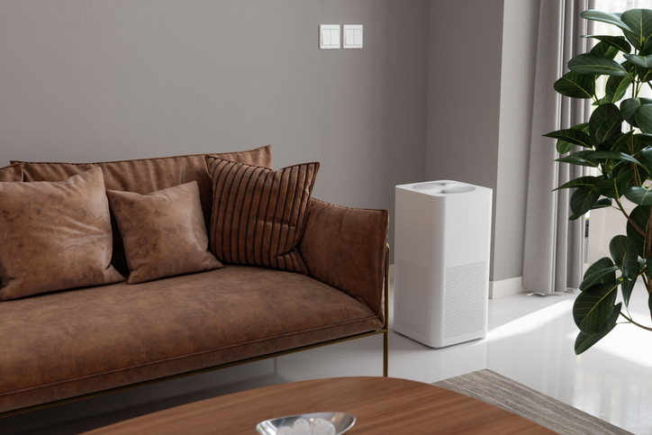 An air purifier is seen next to a couch in a modern living room. 