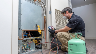 Technician wearing safety goggles and mask checking refrigerant charge on HVAC system