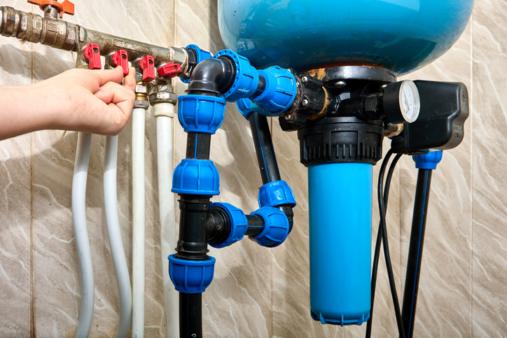 A technician installs a whole house water filter after a pressure tank.