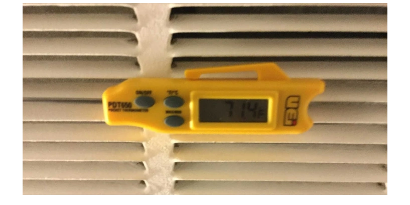 Digital thermometer being used by AC Company to test temperature of airflow in residential home