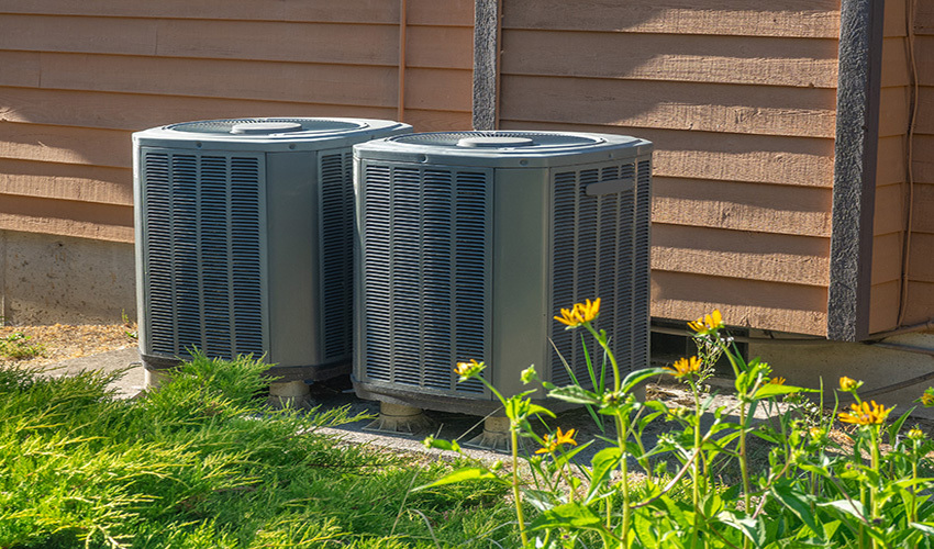 Two air conditioner condensing units outside of home.