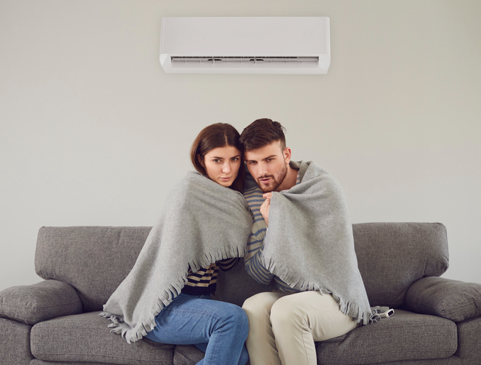 Man and woman wrapping in warm plaid while sitting on sofa | Aire Serv of Wilmington