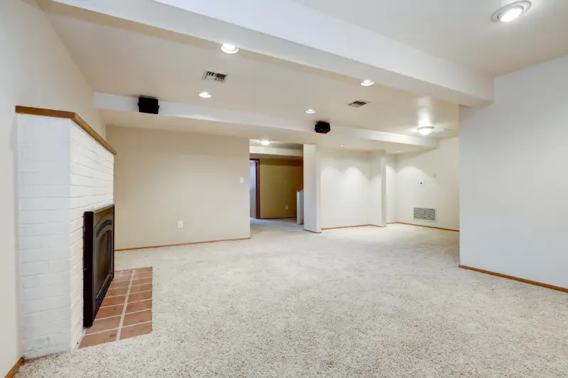 Carpeted basement with fireplace.