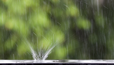 Close-up of raindrop splashing on AC unit.