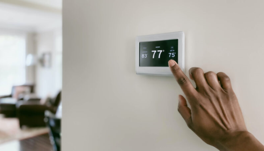 Hand reaching toward touch screen thermostat