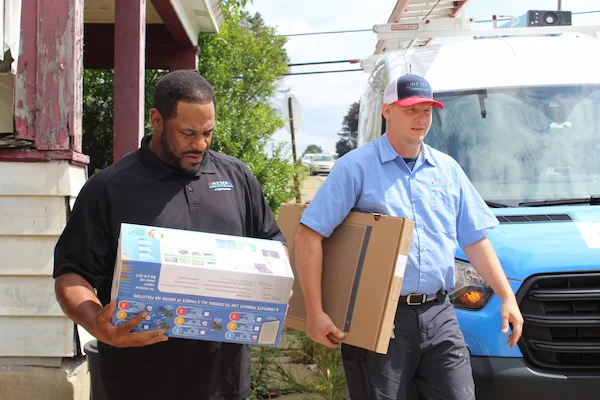 Jerome Bettis walking beside an Aire Serv service professional holding indoor air quality products and a filter.