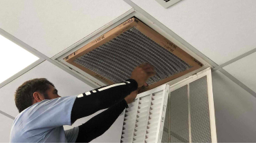 Homeowner changing filters on a whole house fan.