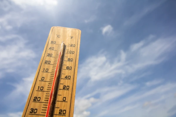 A thermometer reads hot against a blue sky.