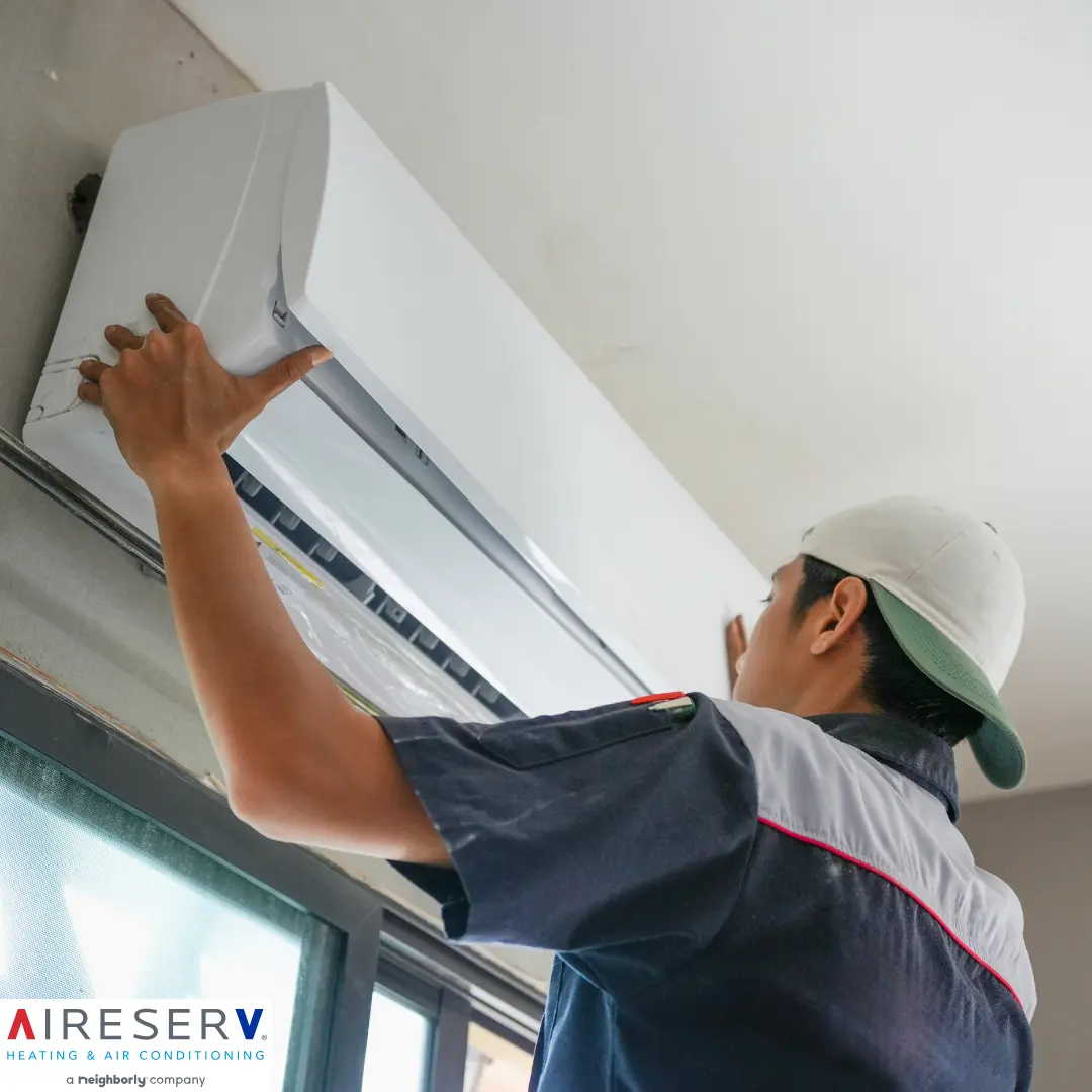 Aire Serv technician inspecting an outdoor AC condenser unit at a West Chester, Pennsylvania home at the end of summer.