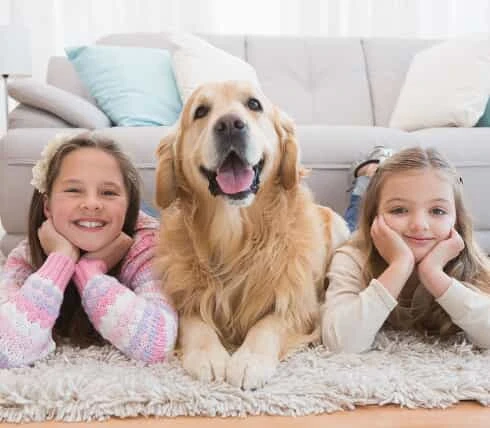 two girls laying on the floor with a Golden Retriever laying in between.
