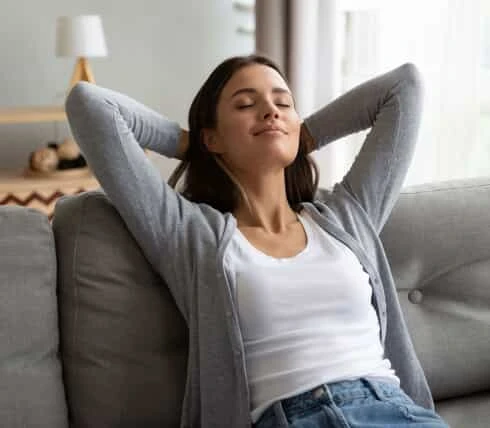 woman relaxing on the couch with her hands behind her head.
